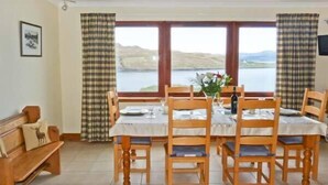 A dining area with a table set for four, wooden chairs, a bench, and a view of a lake. - Mackenzies Peak (Sconser)