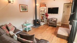 Un salon chaleureux avec un canapé en cuir, une petite table d’appoint, une cheminée, un téléviseur et une tête de cerf décorative accrochée au mur.