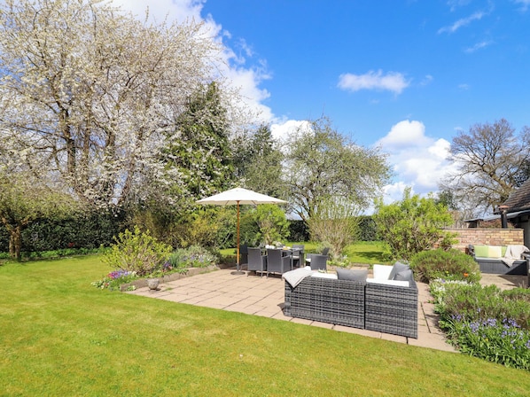 Eine Terrasse mit Gartenmöbeln, einem Tisch und einem Grill.