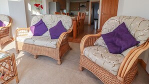 Ein Wohnzimmer mit Korbmöbeln und Blick zur Küche.