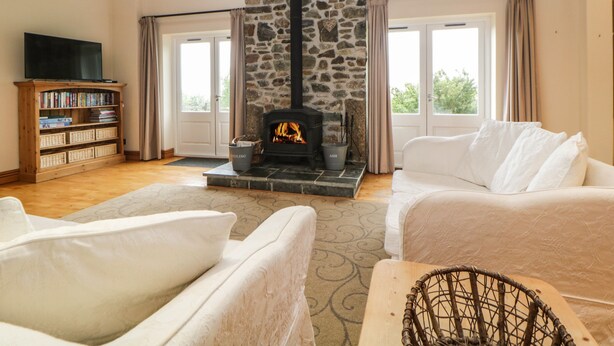 A cozy living room with a stone fireplace, a bookshelf, and a white sofa. - Meader Barn (Tavistock)
