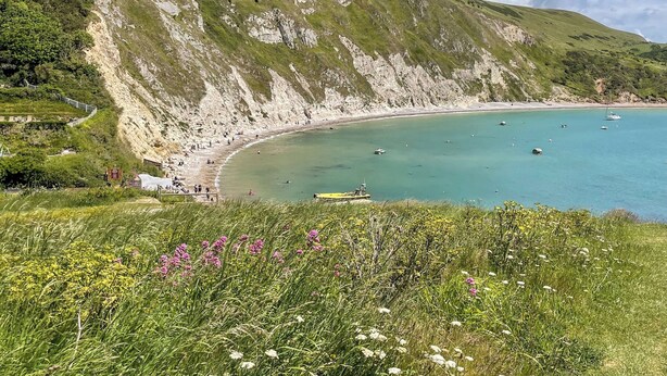 A coastal landscape with a curved bay, cliffs, and a beach.