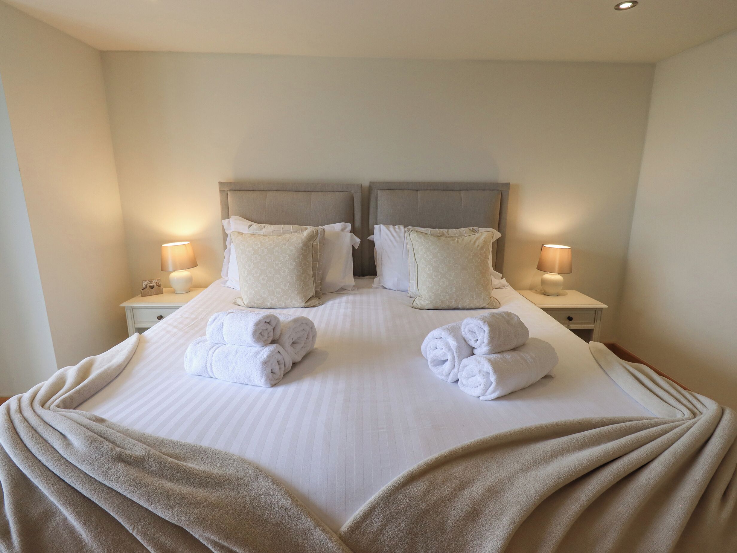 A hotel room with a large bed, two nightstands, and two lamps.