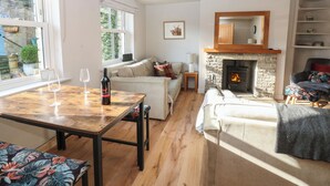 A cozy living room with a fireplace, a dining table with wine glasses, and a sofa. - Hillside View (Hawes)