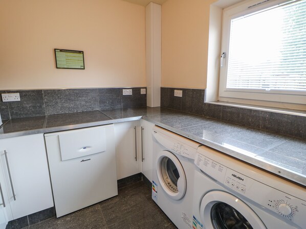 A laundry room with a washing machine, a dryer, and a countertop. - Mead House (Darlington)