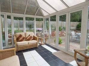 A conservatory with a sofa, chairs, and a tiled floor. - Kemps Eye Cottage (Shrewsbury)