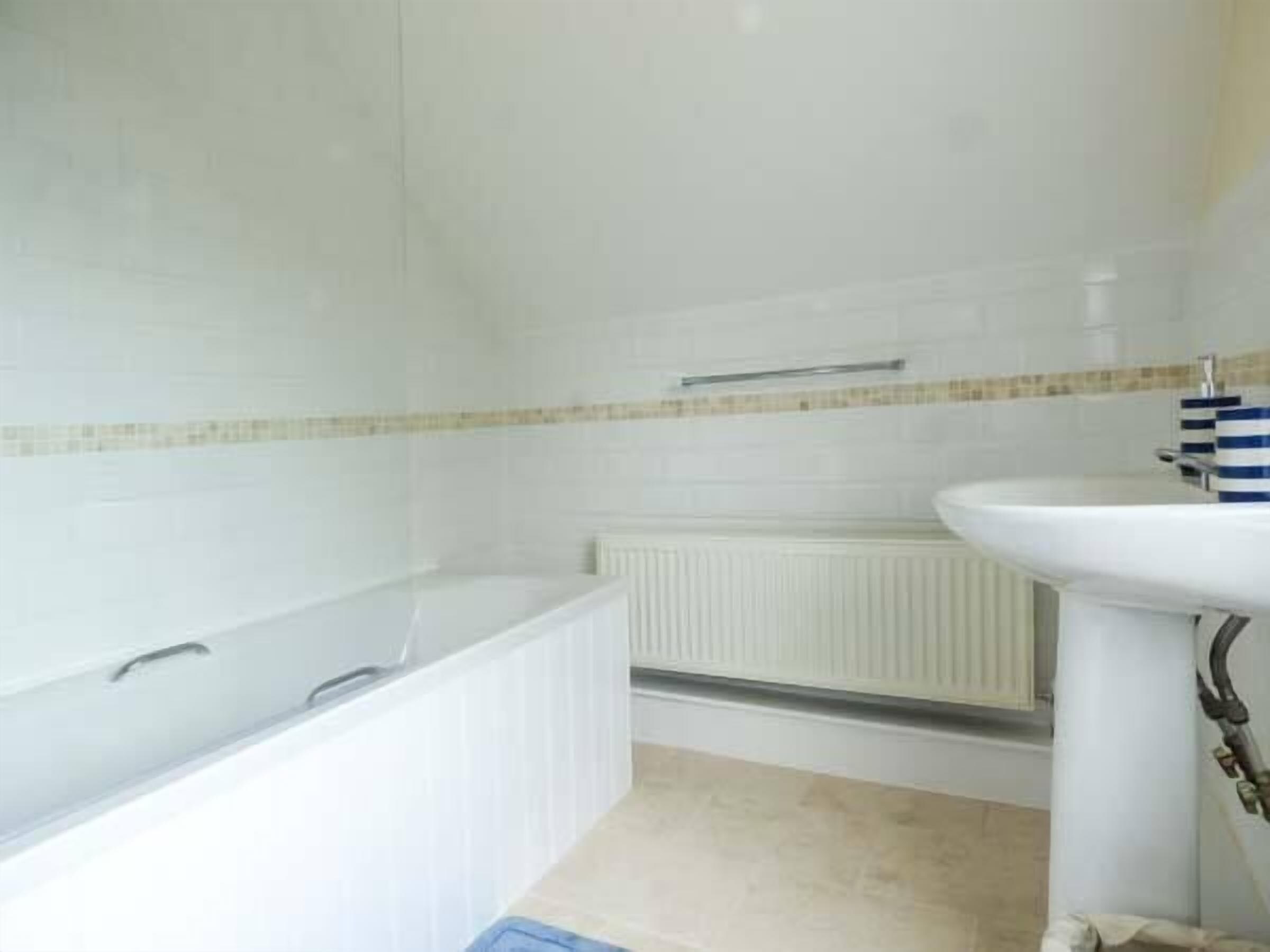 A bathroom with a bathtub, a sink, and a towel rack.