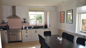 Une cuisine moderne dotée d’un îlot central, d’un four encastré et d’un coin repas avec une table et des chaises.