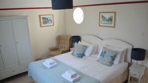 Une chambre à coucher comprenant un lit, une chaise, une armoire et deux tableaux encadrés accrochés au mur.