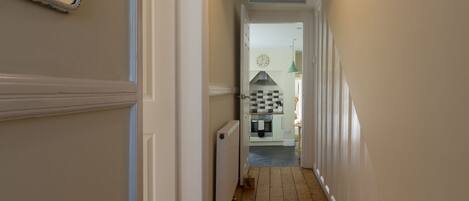 A hallway leading to a kitchen with a clock and a sign reading "BEACH HOUSE".