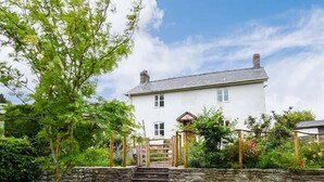 Une maison à deux étages avec un mur en pierre et un portail en bois.