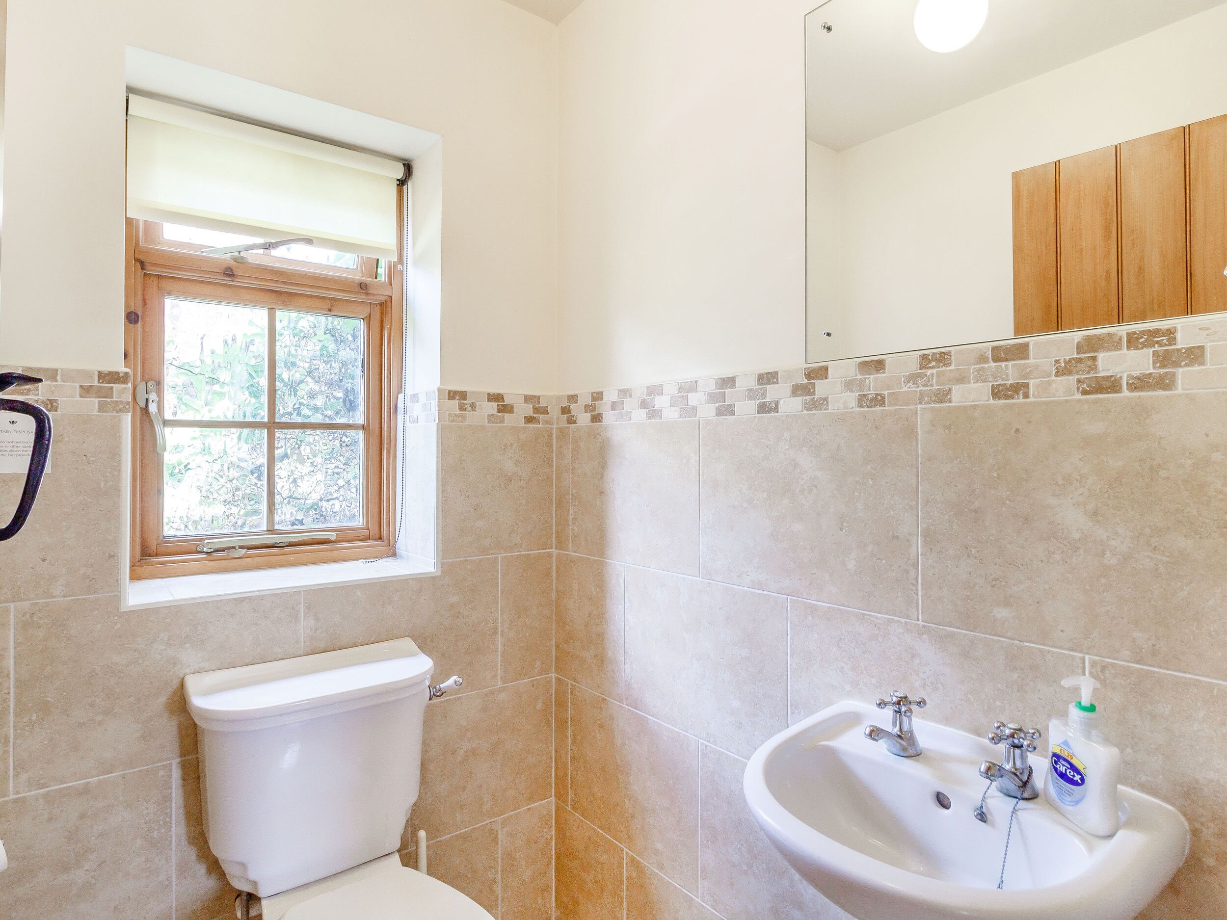 Un baño con inodoro, lavamanos y ventana.