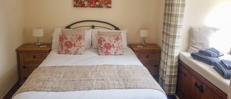 A neatly made bed with floral pillows, a headboard, and bedside tables with lamps.