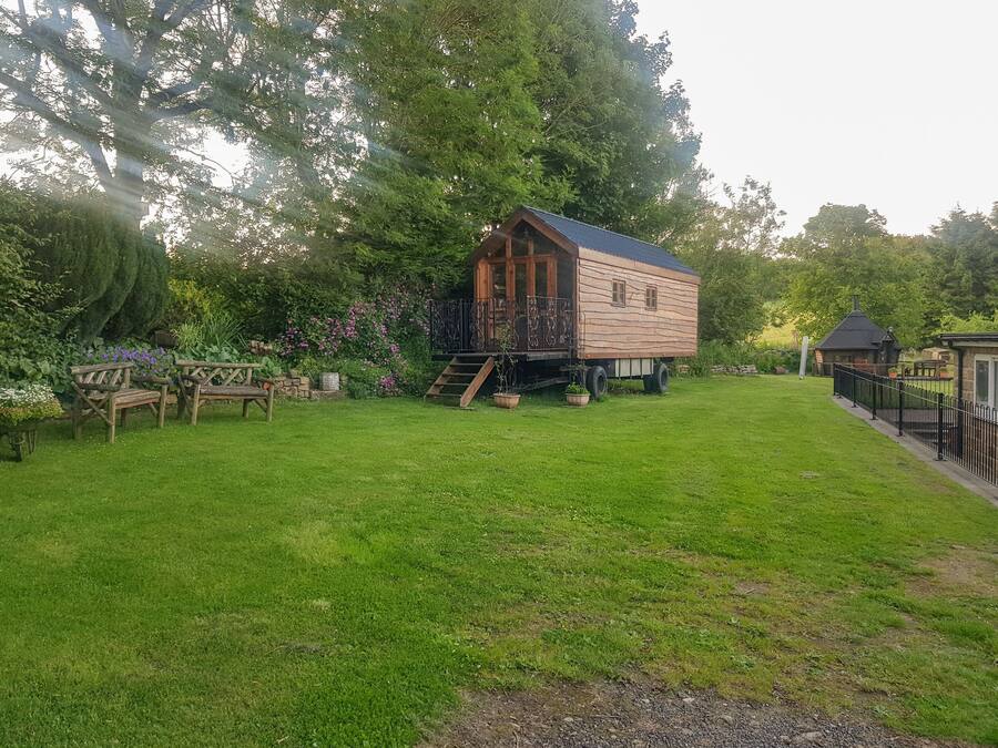 A wooden house with a balcony, surrounded by a well-maintained lawn and garden.