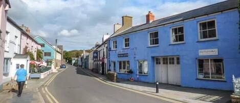 A street with buildings, including a blue building with a sign that reads "The Old Inn."