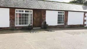 A single-story building with a sloped roof, a wooden door, and two windows. - Faraway Cottage (Carlisle)