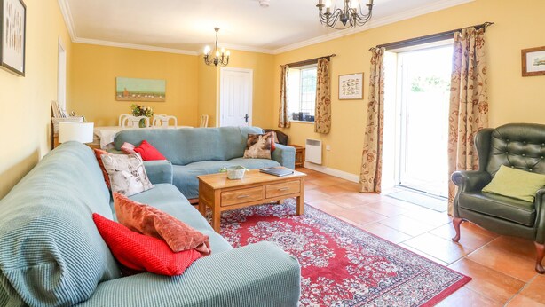 A living room with a sofa, armchairs, a coffee table, and a rug. - The Meadows Cottage (Dereham)