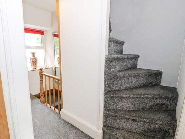 Un escalier avec une rampe en bois et des marches recouvertes de moquette.