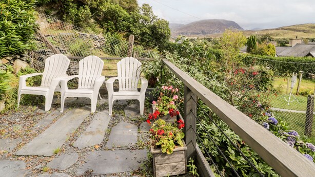 Ein Garten mit zwei weißen Adirondack-Stühlen und einem gepflasterten Weg.