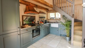 A kitchen with grey cabinets, a wooden ceiling, a sink, and a staircase. - The Tractor Shed (Shrewsbury)