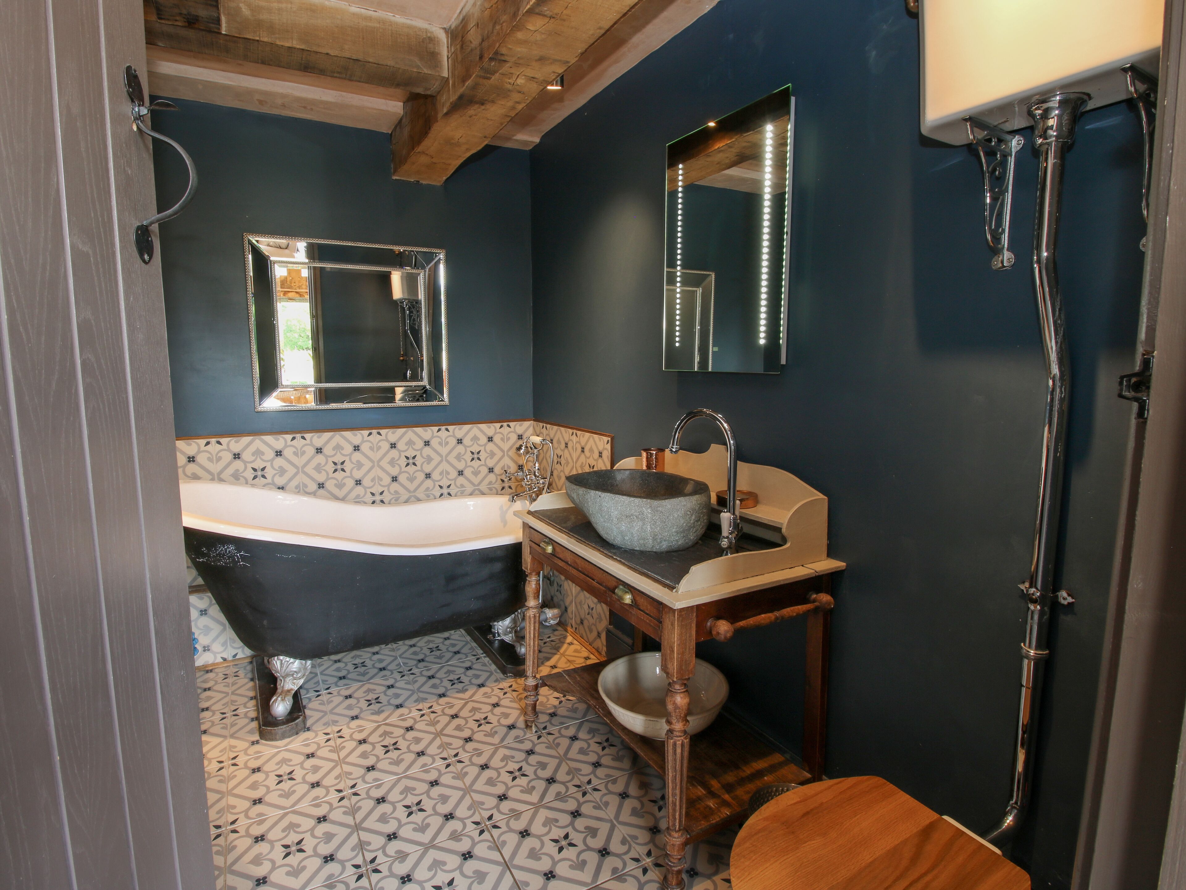 Une salle de bain avec une baignoire, un lavabo avec un receveur en pierre, un miroir avec éclairage intégré et une douche avec une paroi en verre.