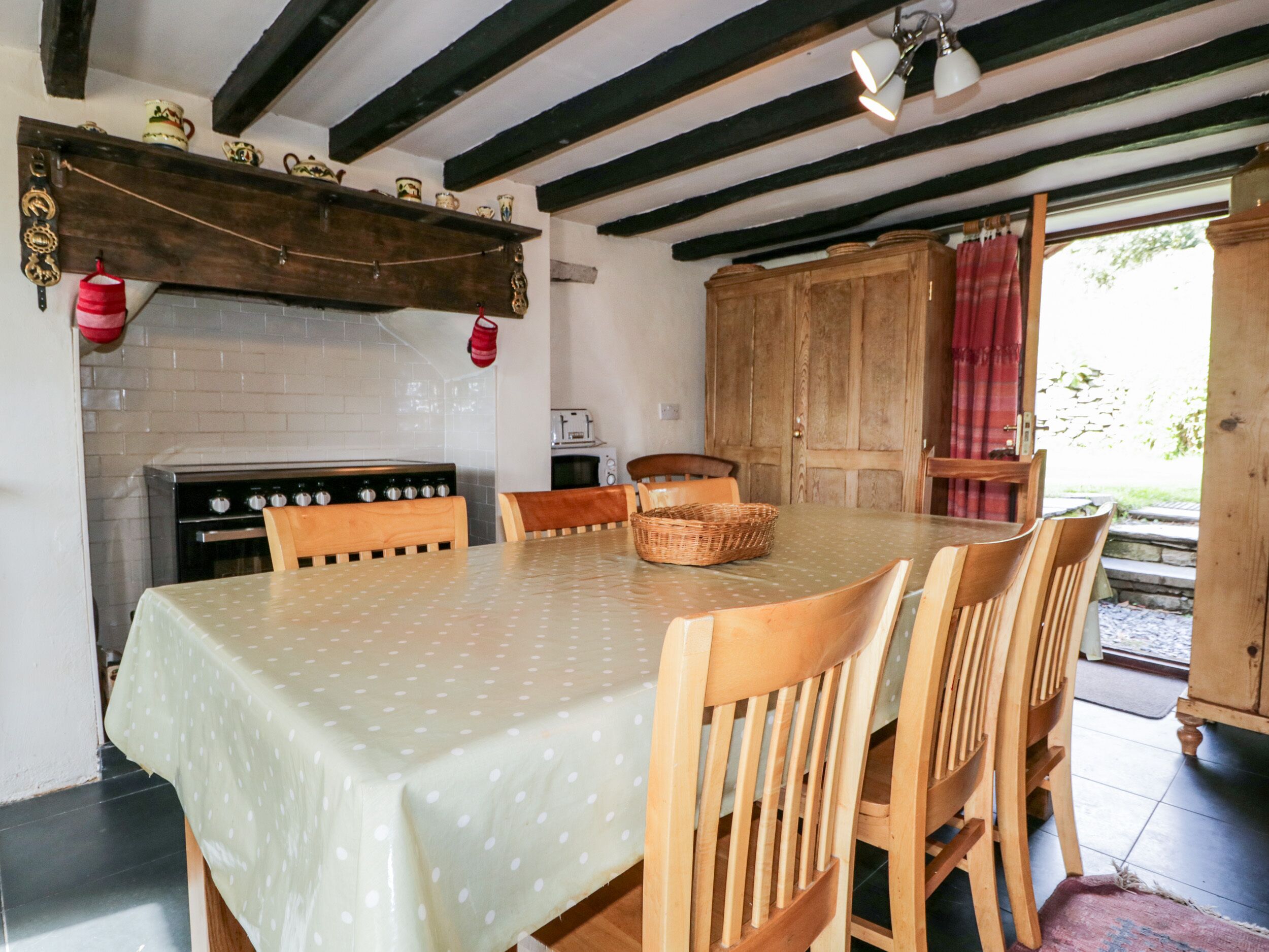 A dining area with a table set for four, wooden chairs, a stove, and a wooden cabinet.