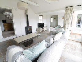 A modern living room with a stone fireplace, a sofa, a TV, and a staircase leading to another room.
