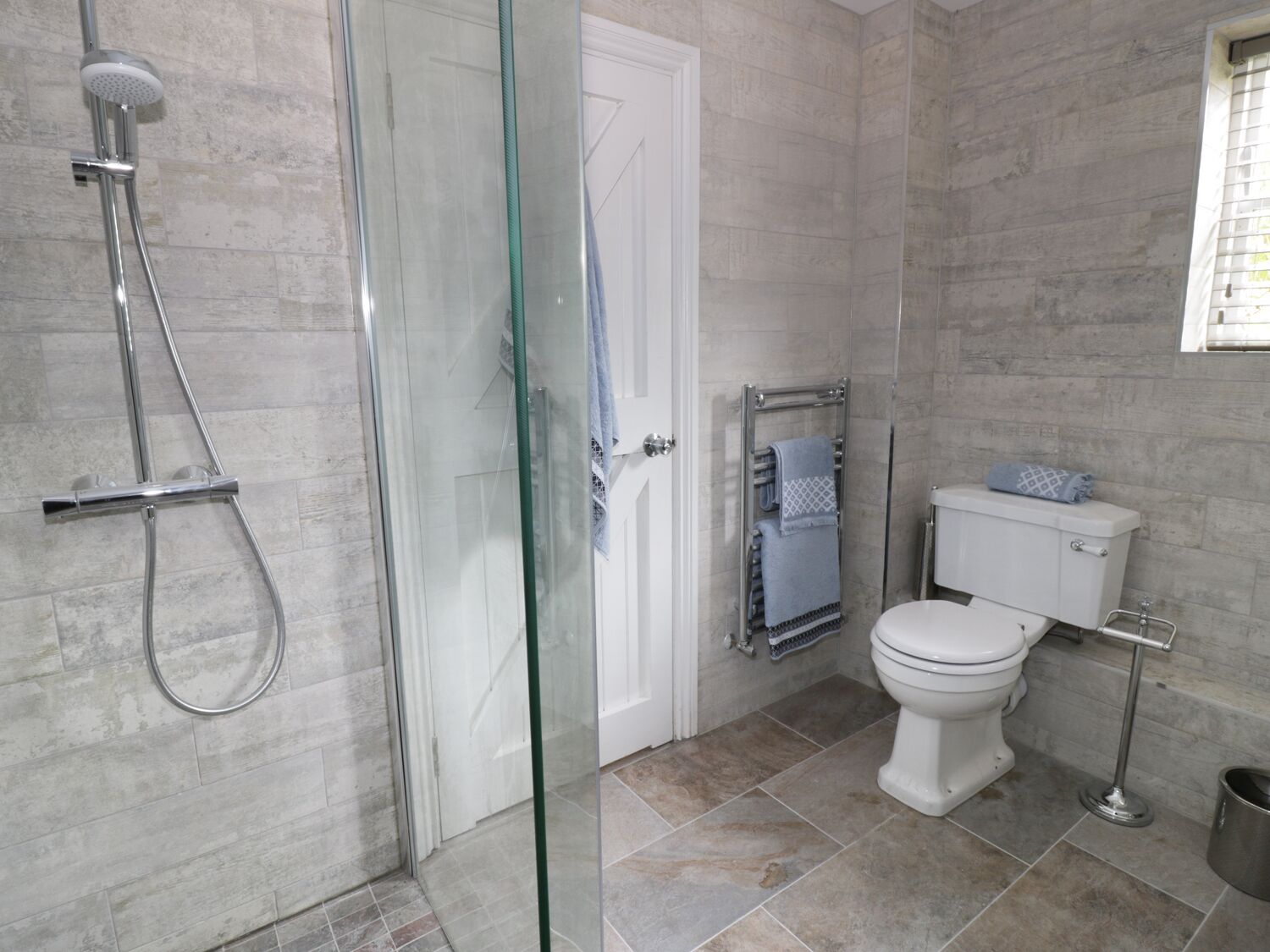 Une salle de bain moderne avec une douche à parois de verre, des toilettes et un porte-serviettes.
