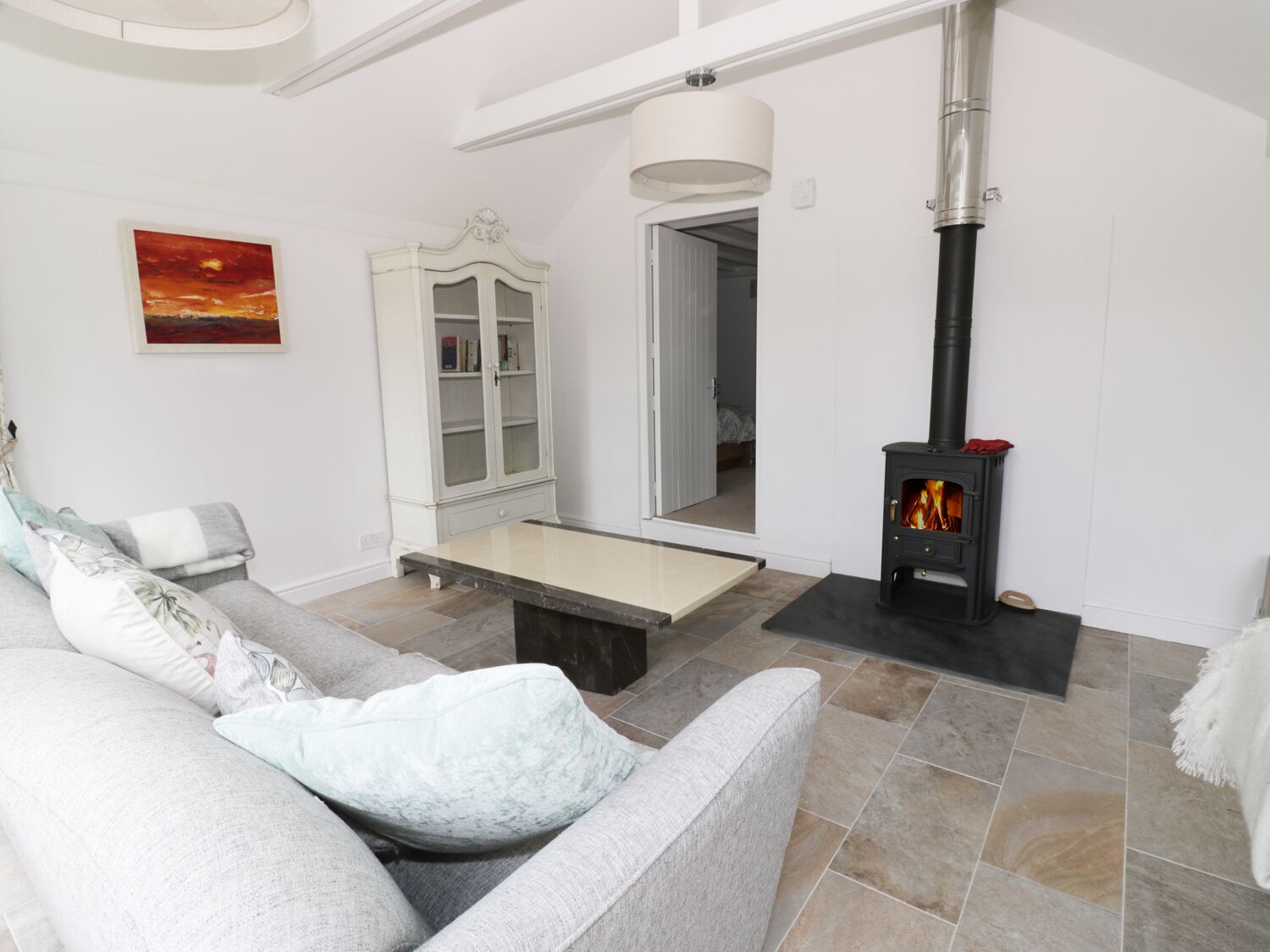 A living room with a sofa, a cabinet, a fireplace, and a painting on the wall.