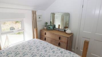 A bedroom with a bed, a dresser, a mirror, and a window.