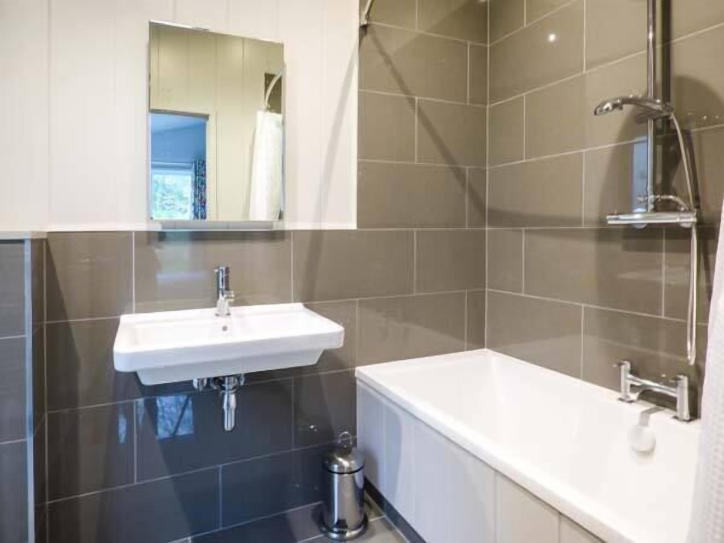A modern bathroom with a white sink, a bathtub, and a shower.