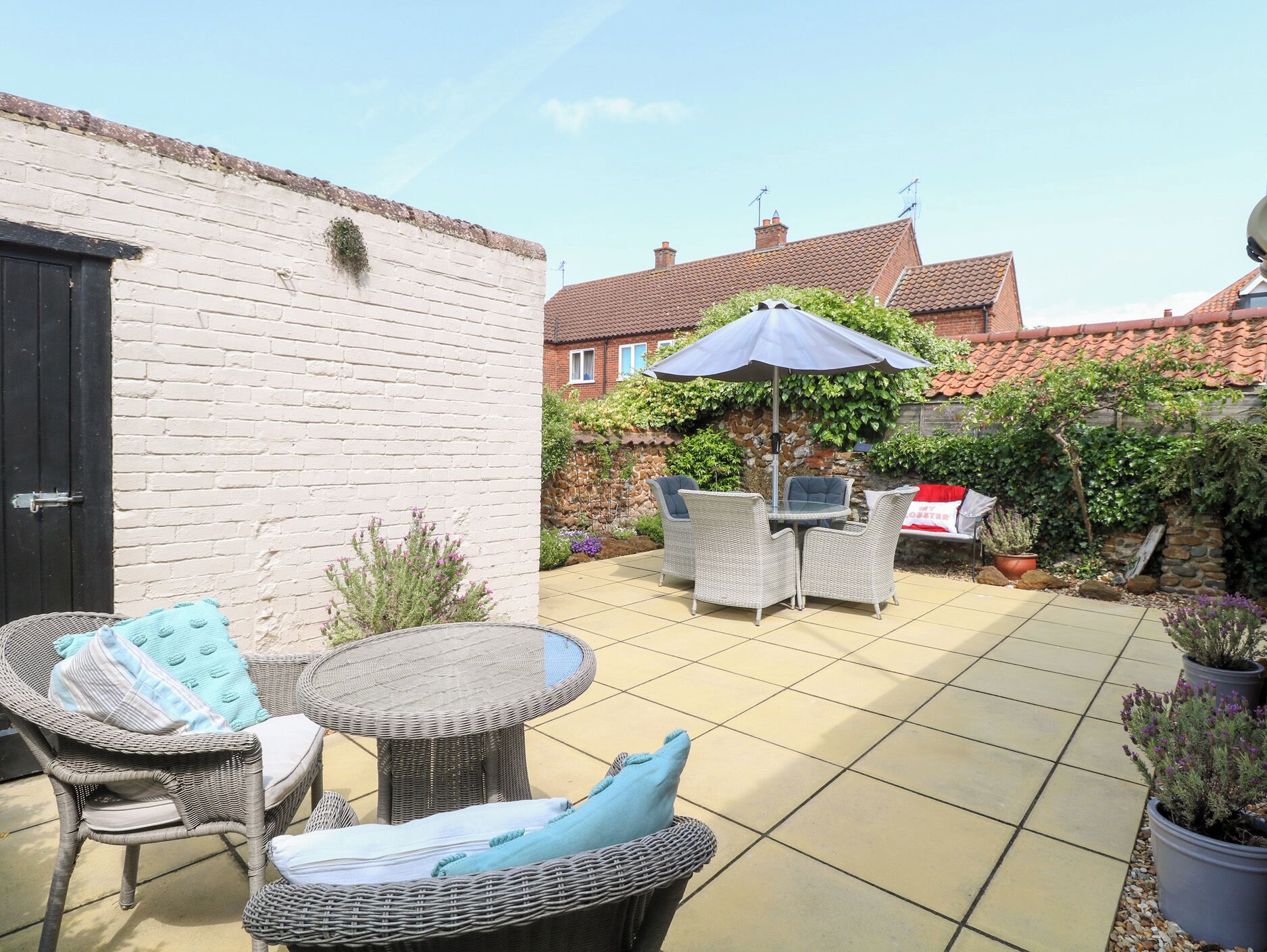 A patio with wicker furniture, a round table, and an umbrella.