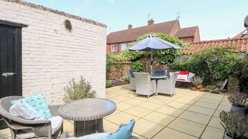 A patio with wicker furniture, a round table, and an umbrella.
