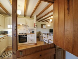 Una cocina con armarios blancos, una estufa y un microondas. Hay una zona de comedor con una mesa y sillas.