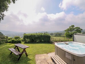 Un patio trasero con una mesa de picnic de madera y un jacuzzi.