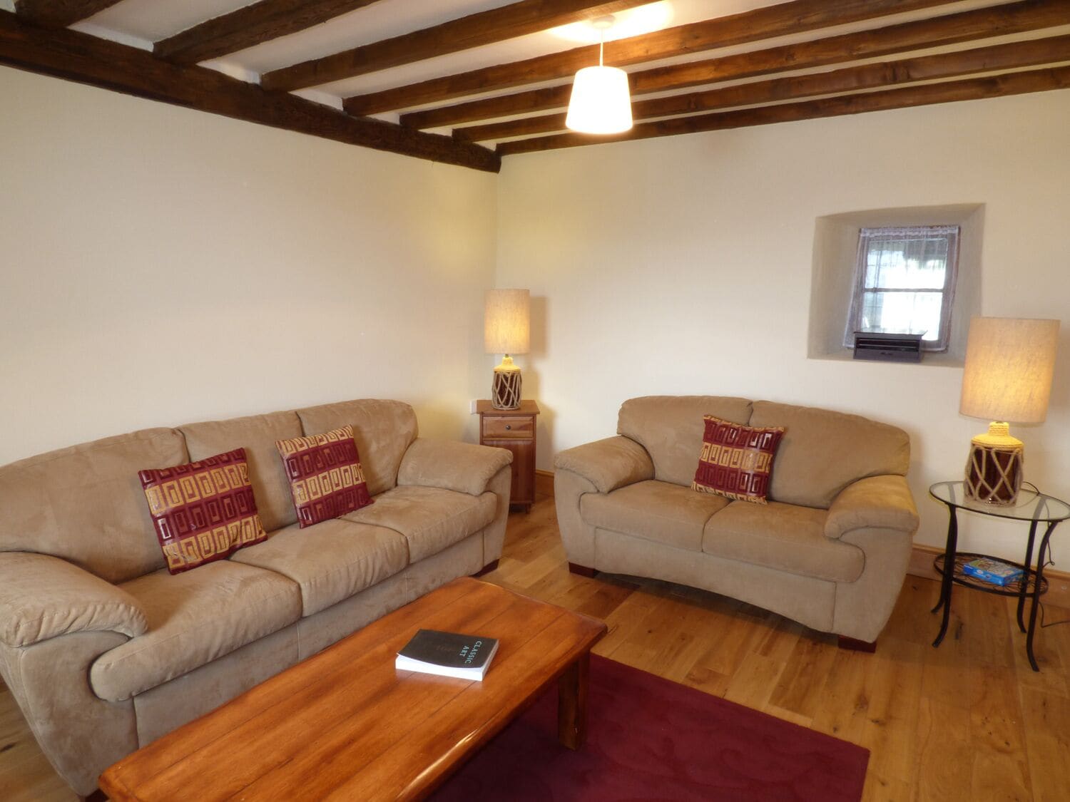 A living room with two beige sofas, a wooden coffee table, and two side tables with lamps.