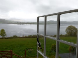 Vista de un lago desde una ventana con una reja metálica al frente.