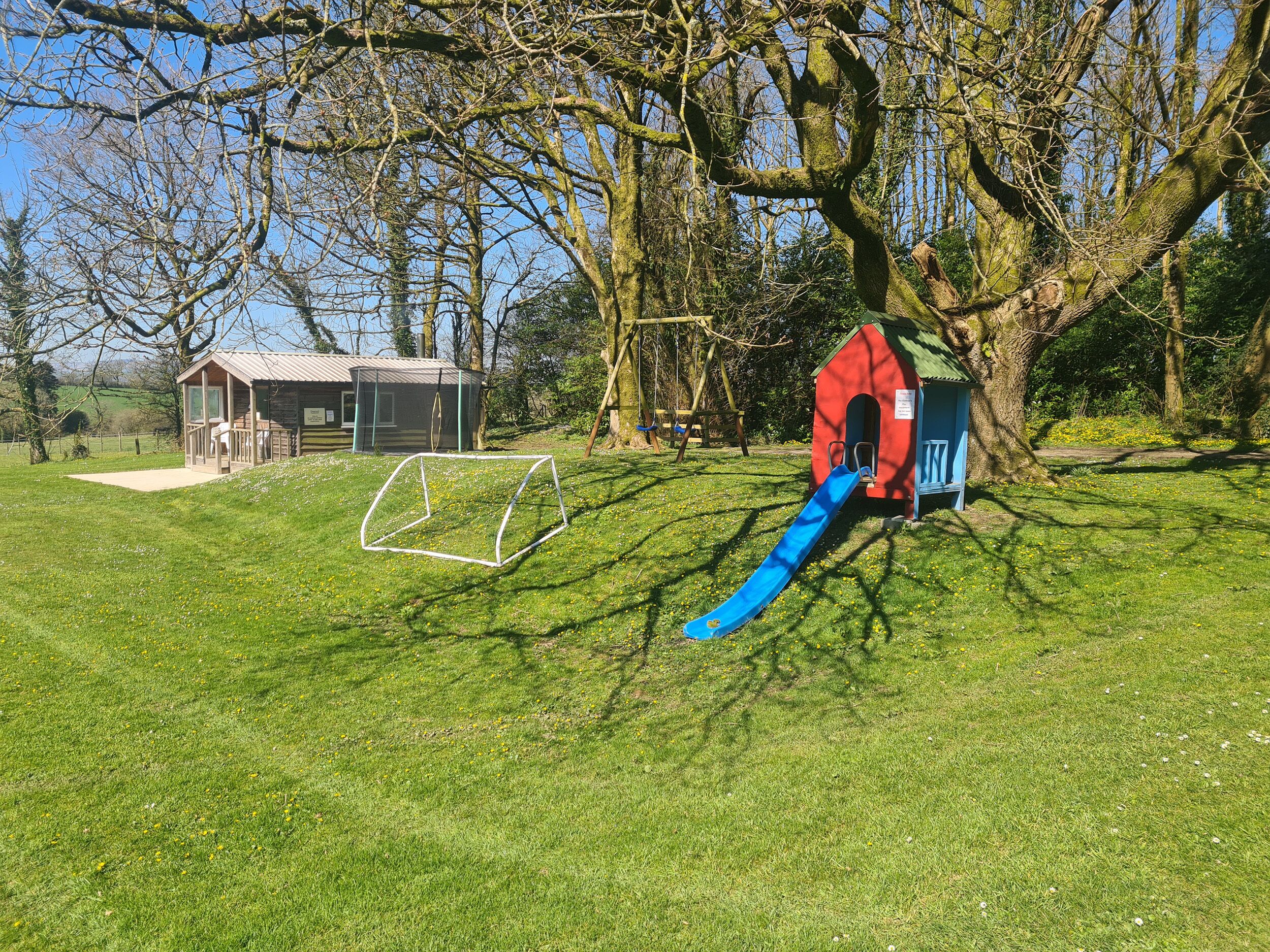 Un parque infantil con un tobogán y una casita roja.