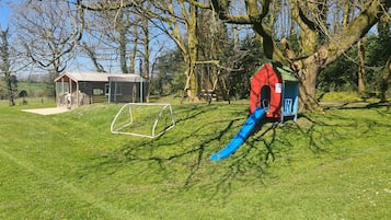Un parque infantil con un tobogán y una casita roja.