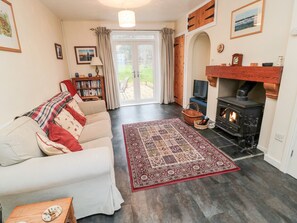 A cozy living room with a fireplace, a sofa, a rug, and a bookshelf. - Bunty's Place (Alnwick)