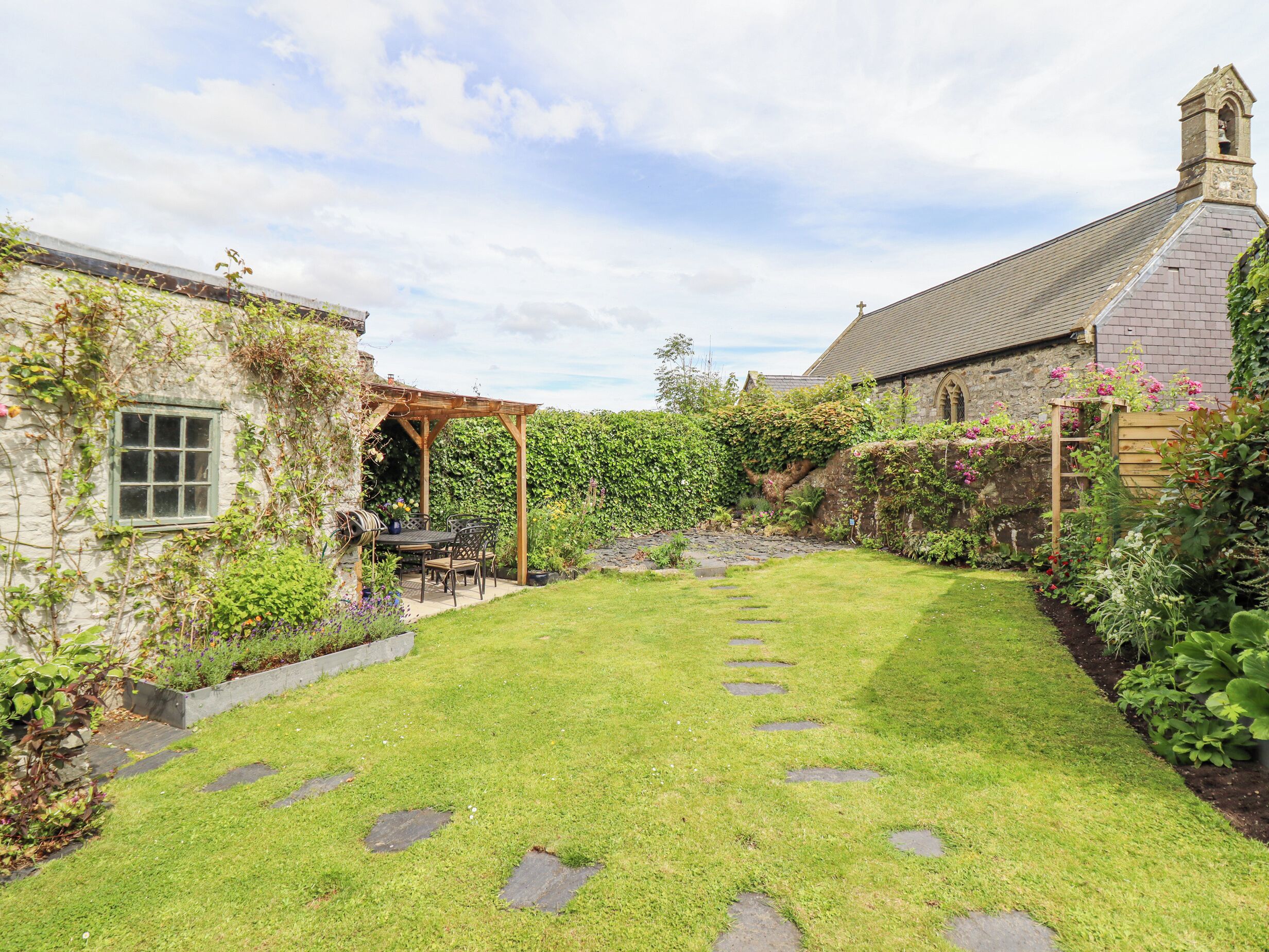 A stone building with a garden patio, stone steps, and a lawn.