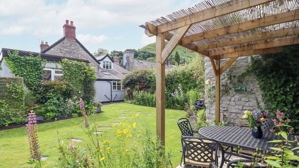 A garden with a pergola, outdoor seating, and a stone wall. - Bodywen (Oswestry)
