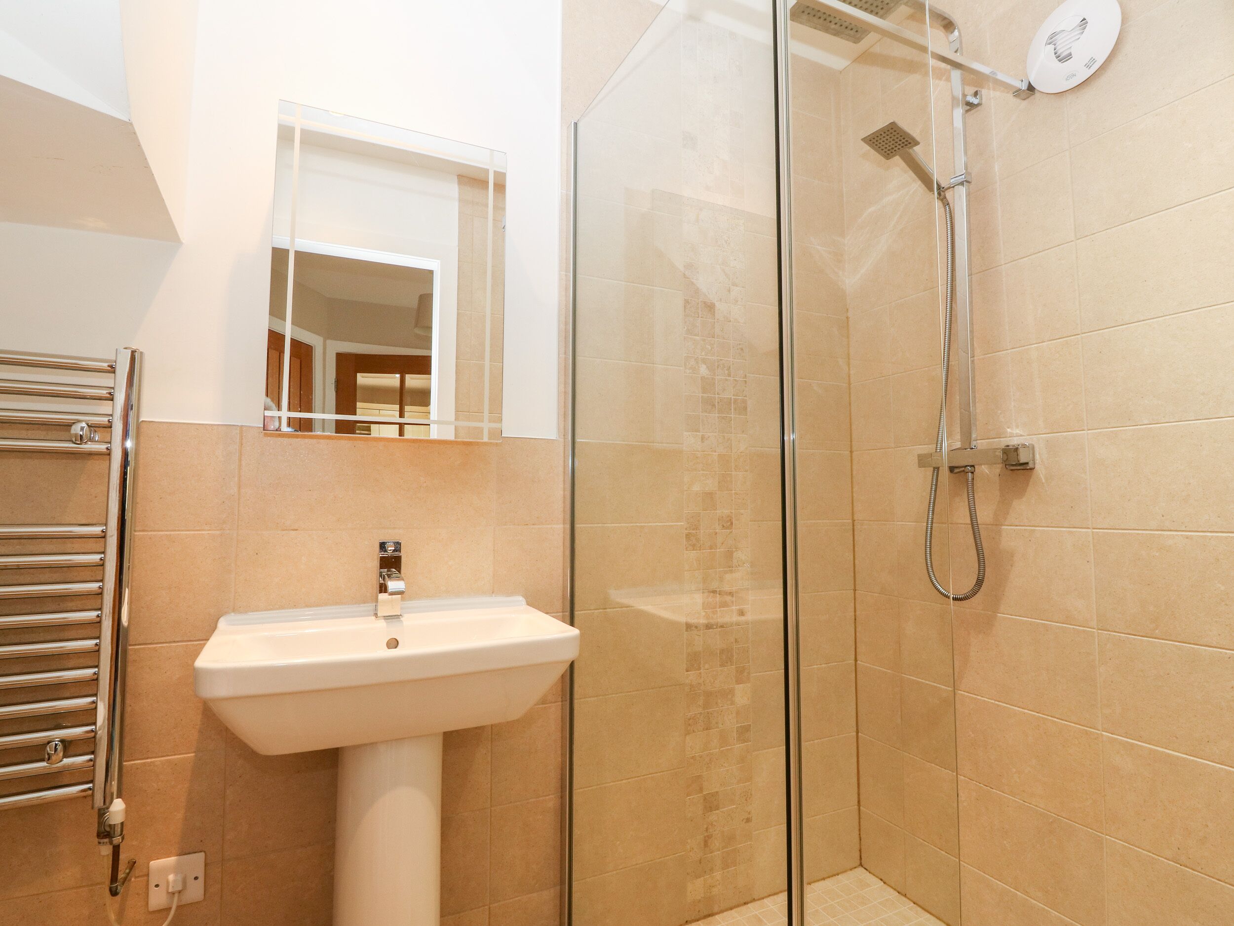 A bathroom with a glass-enclosed shower, a white pedestal sink, and a towel rack.