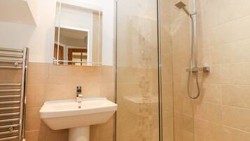 A bathroom with a glass-enclosed shower, a white pedestal sink, and a towel rack.