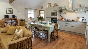Una sala de estar acogedora con comedor, muebles de madera y una cocina equipada con electrodomésticos modernos.