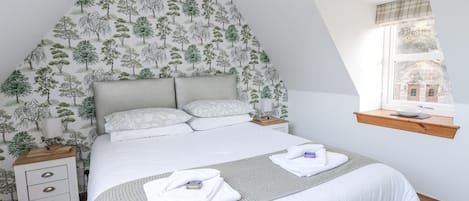 Quarto com cama, mesas de cabeceira, janela com vista e parede com padrão de árvore.