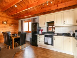 A wooden interior with a dining area, kitchen, and a window with curtains.