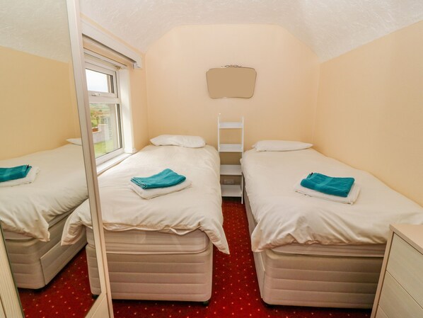 Habitación doble con dos camas, una ventana y un espejo.