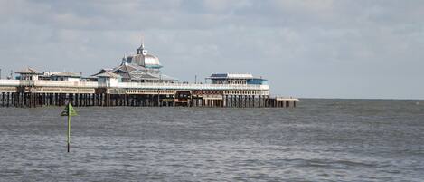 A pier extending into the water with a building featuring a large dome and multiple levels.