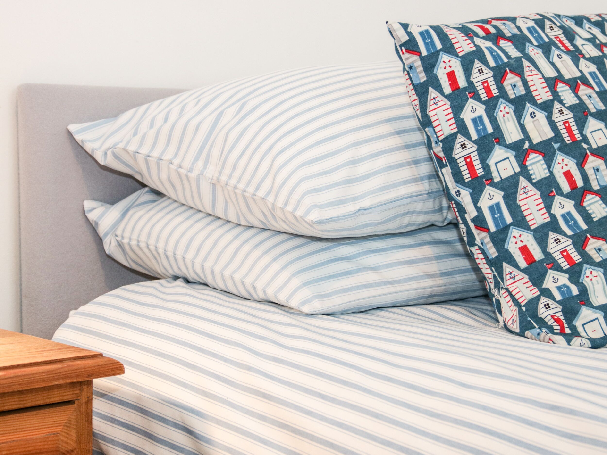 A bed with striped bedding and a pillow with a nautical theme.